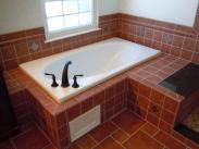 A new soaking tub with decorative tile work around the wall and an easy access panel