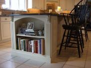 Elegant built in book shelves in the center island make access to recipes easy